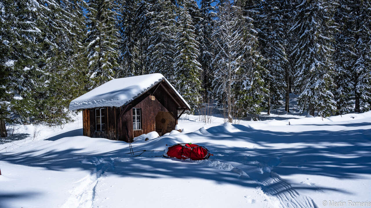 Pulka devant une cabane dans la neige