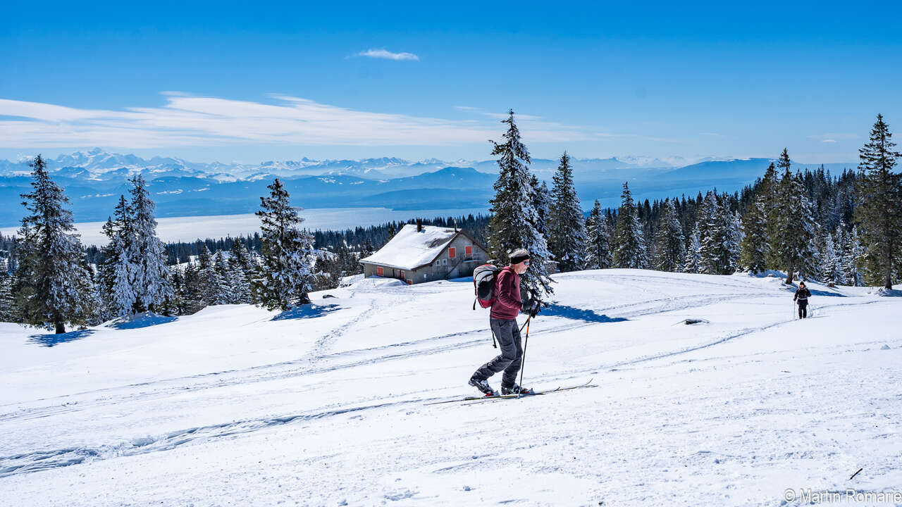 Skieur devant un paysage de montagne et une cabane