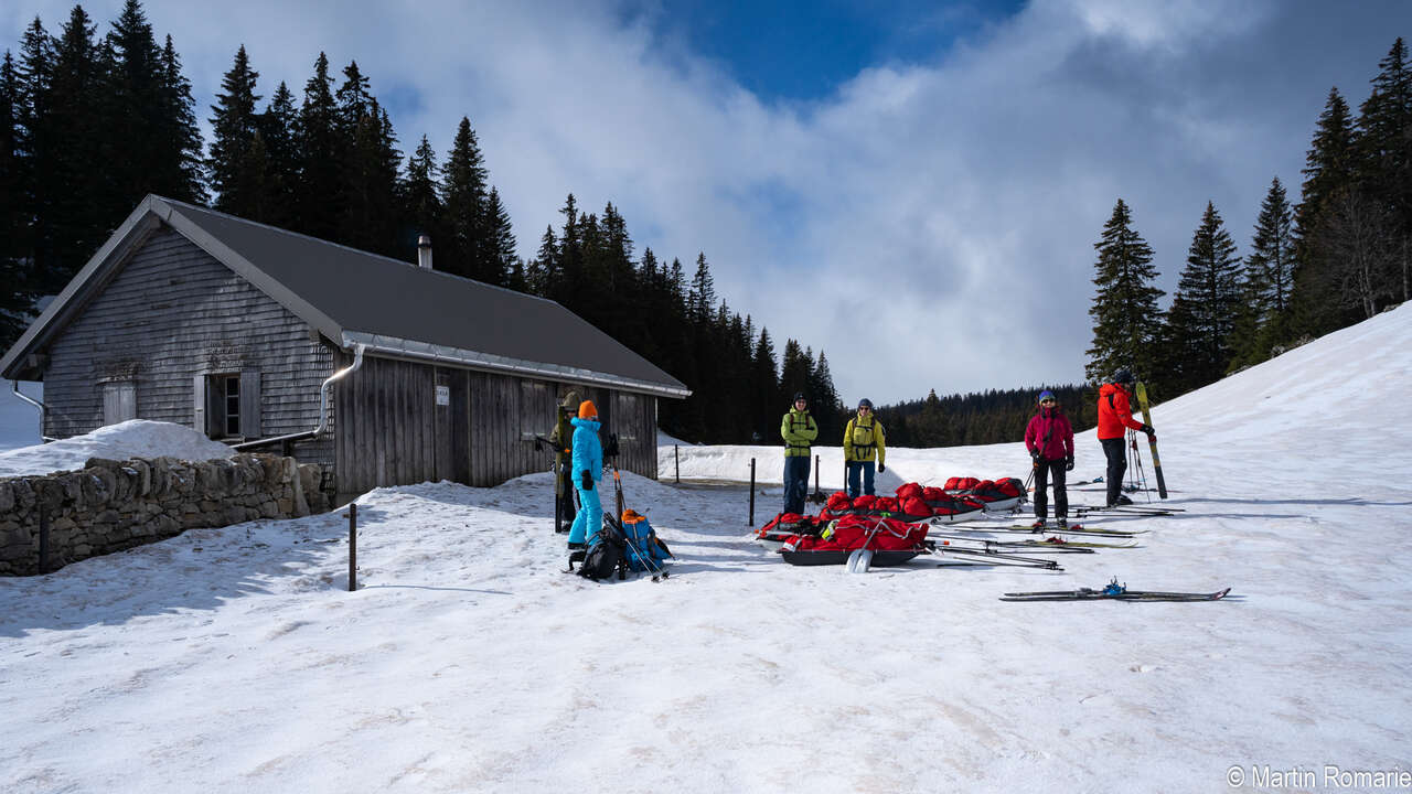 Skieurs et pulka devant une cabane