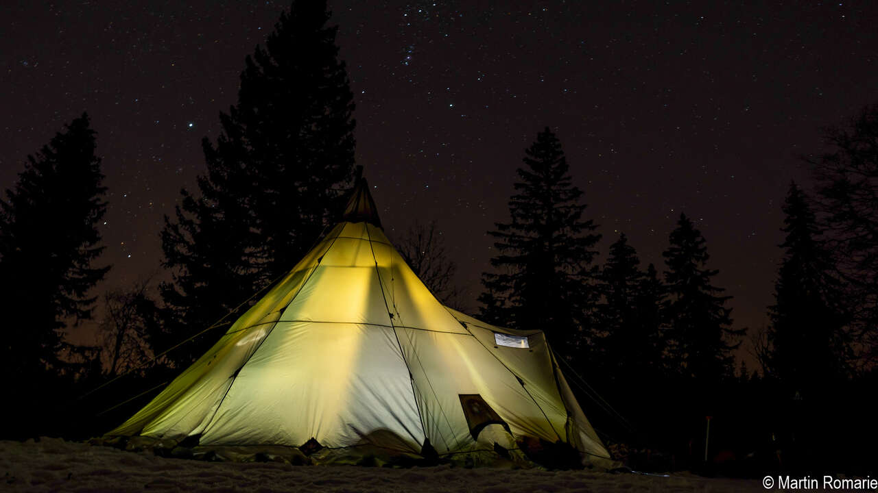 Tente dans la neige sous les étoiles